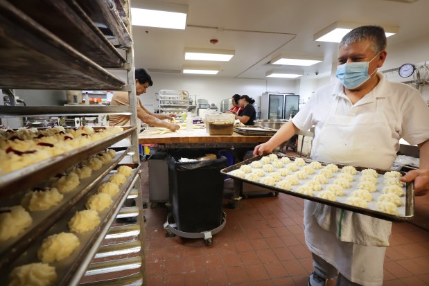 Oscar Sanchez carries a tray of macaroons at Kaufman's Bagel & Delicatessen on April 12, 2024, in Skokie. (Stacey Wescott/Chicago Tribune)