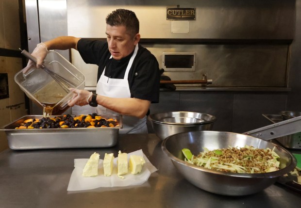 Fernando Gomez prepares a batch of tzimmes, made with sweet root vegetables, at Kaufman's Bagel & Delicatessen on April 12, 2024, in Skokie. It is one of the specialty items they make for Passover. (Stacey Wescott/Chicago Tribune)