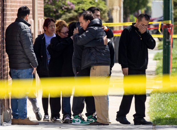 People embrace as Chicago police investigate the scene where an off-duty officer was shot and killed overnight on April 21, 2024, in the 3100 block of West 56th Street in Gage Park. (Brian Cassella/Chicago Tribune)