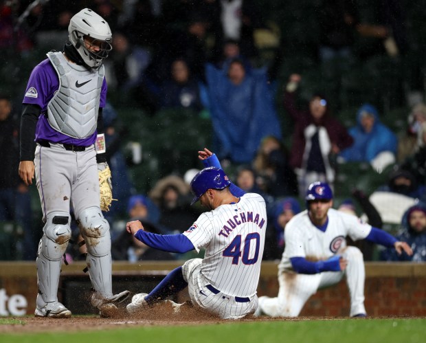 Chicago Cubs baserunner Mike Tauchman (40) slides in safely at home plate to score on a throwing error that resulted from a two-run single by Cubs catcher Miguel Amaya in the sixth inning of a game against the Colorado Rockies at Wrigley Field in Chicago on Wednesday, April 3, 2024. (Chris Sweda/Chicago Tribune)