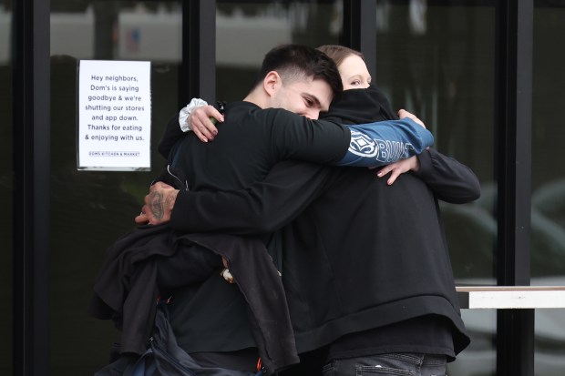 People hug outside the Dom's Kitchen & Market on Halsted Street at Diversey Parkway in Chicago after the store was abruptly closed and employees were let go on April, 23, 2024. (Terrence Antonio James/Chicago Tribune)