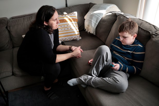 Jennifer Schuh tries to get her son B., 8, who is Autistic, off the game, while at their home in Westmont, Feb. 23, 2024. (Antonio Perez/Chicago Tribune)