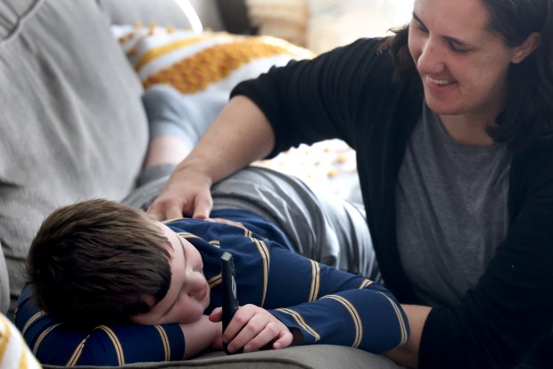 Jennifer Schuh tenderly messages and calms her son B., 8, who is Autistic, at their home in Westmont, Feb. 23, 2024. (Antonio Perez/Chicago Tribune)