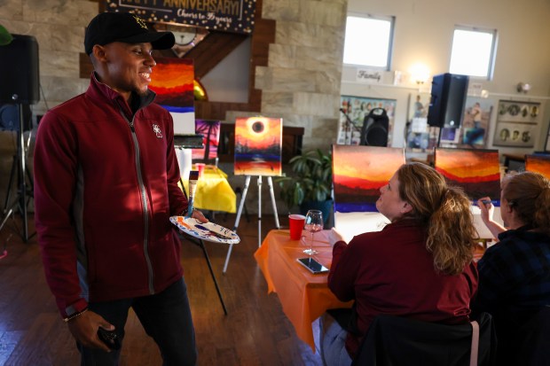 Marquez Scoggin, co-founder and co-owner of Project Human X, left, speaks to Sonia Beckmann as he leads an eclipse-themed painting class on April 5, 2024, at Alto Vineyards in Alto Pass. The Downstate vineyard is in the path of totality. (Eileen T. Meslar/Chicago Tribune)