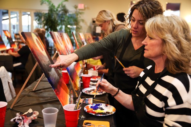 Jaci Fitchpatrick, left, of Peoria, speaks to Shari Humes, of Galesburg, while they attend an eclipse-themed painting class on April 5, 2024, at Alto Vineyards in Alto Pass. (Eileen T. Meslar/Chicago Tribune)