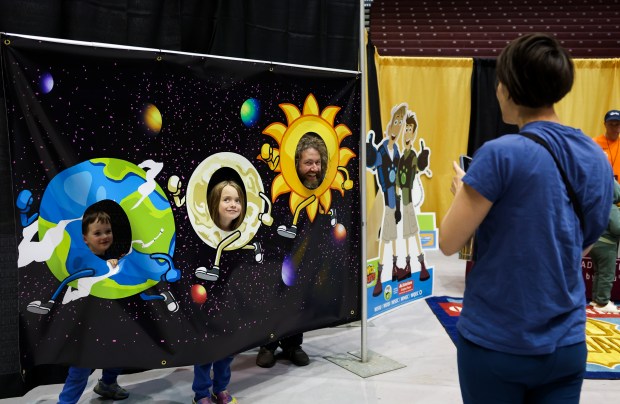 Sara Ressing, right, takes a photo of her husband, Elliott Zieman, and their sons, Harrison Zieman, 6, and Darwin Zieman, 3, during the Crossroads Astronomy, Science and Technology Expo at Southern Illinois University in Carbondale on April 7, 2024.(Eileen T. Meslar/Chicago Tribune)