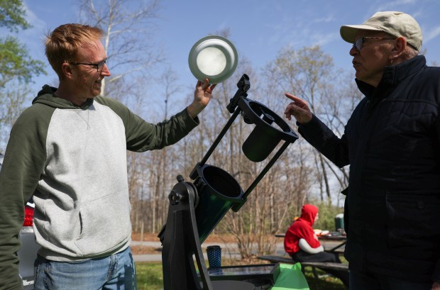 CJ Dugan, a producer at WGN, shows retired WGN-TV meteorologist Tom Skilling his reflector telescope at Dugan's friend's campsite at Little Grassy Lake Campground in Makanda on April 7, 2024. Dugan and his family witnessed the 2017 eclipse with Skilling. (Eileen T. Meslar/Chicago Tribune)