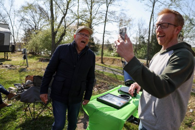 Retired WGN-TV meteorologist Tom Skilling, left, says hello to the father of CJ Dugan on FaceTime at Little Grassy Lake Campground in Makanda on April 7, 2024. Dugan, a producer at WGN, and his family witnessed the 2017 eclipse with Skilling. (Eileen T. Meslar/Chicago Tribune)