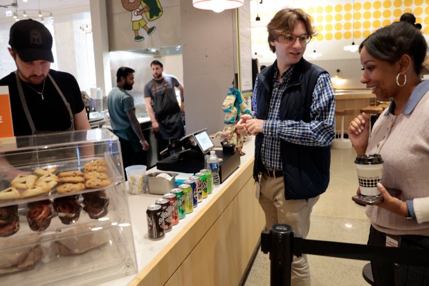 Customers Taylor Robinson, center, and Niesha Griffin put in their take out orders at Zeitlin's Delicatessen, on April 9, 2024, inside the Old Post Office in Chicago. At the counter is Zeitlin's owner, Sam Zeitlin's. (Antonio Perez/Chicago Tribune)