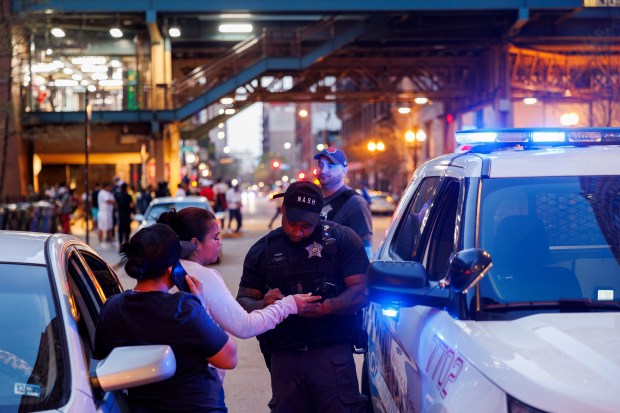Officers issue a ticket to a migrant for parking in a no parking zone near the migrant shelter at the former Standard Club on April 15, 2024, in Chicago. (Armando L. Sanchez/Chicago Tribune)