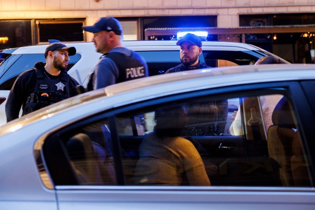 Officers issue a ticket to a migrant for parking in a no parking zone near a migrant shelter at the former Standard Club on April 15, 2024, in Chicago. (Armando L. Sanchez/Chicago Tribune)