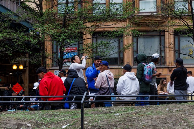 Migrants gather in Pritzker Park near the the former Standard Club shelter on April 17, 2024, in Chicago. (Armando L. Sanchez/Chicago Tribune)