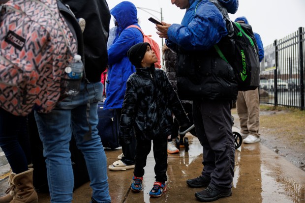 Johangel Barrios, 5, looks up at his father, Keywell Barrios, both from Venezuela, while waiting for a bus outside a migrant shelter on the Lower West Side on March 8, 2024 in Chicago. (Armando L. Sanchez/Chicago Tribune)