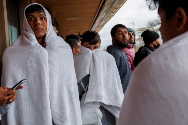 Migrants wait for a Chicago-bound train at a Metra station after traveling by bus from El Paso, Texas, April 3, 2024, in Wilmette. (Armando L. Sanchez/Chicago Tribune)