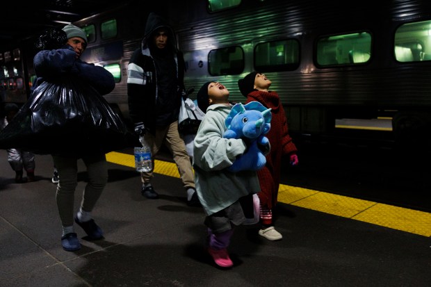 Leannysmar Ruiz, 7, From right, and her sister, Lismar Ruiz, 6, try to see their breath while walking with other migrants after riding a Metra train from Wilmette to Chicago's Ogilvie Transportation Center, April 3, 2024, in Chicago. (Armando L. Sanchez/Chicago Tribune)