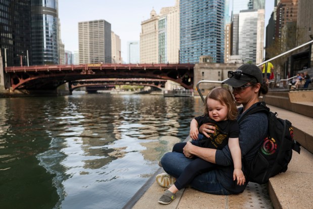 Michael Cameron and his son, James, sit on the Chicago Riverwalk between Dearborn and State streets on April 22, 2024. (Eileen T. Meslar/Chicago Tribune)