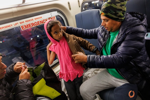 Mientras viaja en un tren de Metra, Jean Carlos, de 40 años, le pone una chaqueta donada a su hija, Sofía Zambrano, de 8 años, luego de viajar desde El Paso, Texas, el 3 de abril de 2024, en Wilmette. (Armando L. Sánchez/Chicago Tribune)