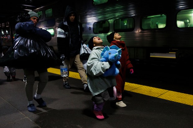Leannysmar Ruiz, de 7 años, de derecha a izquierda, y su hermana, Lismar Ruiz, de 6, caminan con otros inmigrantes después de viajar en un tren Metra desde Wilmette hasta el Centro de Transporte Ogilvie de Chicago, el 3 de abril de 2024, en Chicago. (Armando L. Sánchez/Chicago Tribune)
