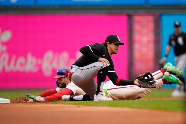 Philadelphia Phillies' Bryce Harper, left, slides into second base past Chicago White Sox shortstop Nicky Lopez to advance after a throwing error on a pickoff attempt during the first inning of a baseball game, Sunday, April 21, 2024, in Philadelphia. (AP Photo/Matt Slocum)