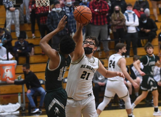Oak Forest's Robbie Avila (21) blocks a shot by Evergreen Park's Malik Kelly (12) during a South Suburban Conference crossover game in Oak Forest on Friday, Jan. 7, 2022.
