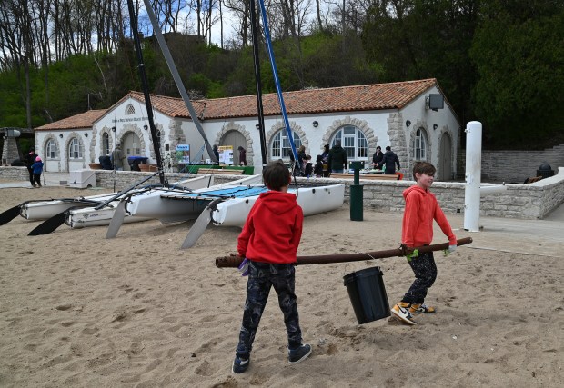 From left to right, Highland Park siblings Sean Collins, a fourth-grader and Jack Collins, a sixth-grader, carry an approximate 50 pound metal pole found on the shoreline past the boathouse at the Earth Day Clean-Up event at Glencoe Beach on April 20, 2024 in Glencoe. (Karie Angell Luc/Pioneer Press)