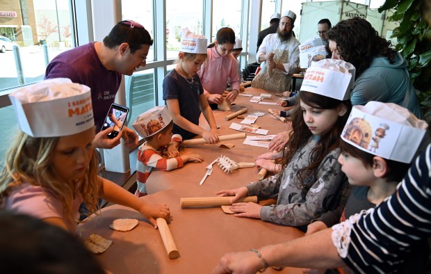 Center, top, Rabbi Schenur Scheiman of Des Plaines, who operates Camp Gan Israel of Northbrook, oversees a rolling pin task at the Model Matzah Bakery, a family matzah bake by Chabad of Northbrook at Mariano's in Northbrook on April 15, 2024. (Karie Angell Luc/Pioneer Press)