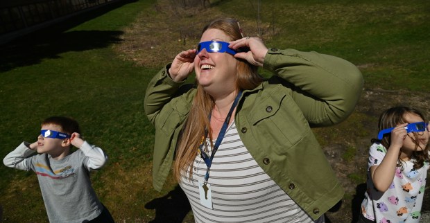 Center, Corrie Tucker, Greenbriar School first grader teacher, views the solar eclipse with the class at Greenbriar School in Northbrook on April 8, 2024. (Karie Angell Luc/for the Pioneer Press)