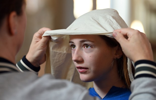 From left, parent Erin Bretts of Glenview affixes the headwear of daughter Maddie Bretts, 11, a fifth-grader. Maddie will portray a woman from Jerusalem during the Stations of the Cross at Our Lady of Perpetual Help Church in Glenview on Good Friday, March 29, 2024. (Karie Angell Luc/for the Pioneer Press)