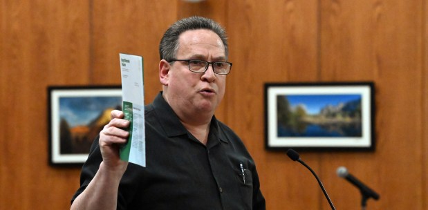 Holding the Northbrook Voice village newsletter to make a point, David Petrich of Northbrook speaks to trustees with concerns about the pending sale of the 1657 Shermer Road Village of Northbrook owned property during the April 9, 2024 Northbrook Village Board of Trustees meeting. (Karie Angell Luc/for the Pioneer Press)