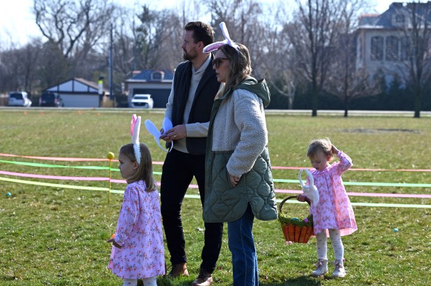 Note on right that bunny ears are falling off of Clara Winnett, 2, of Winnetka. From left is Clara's sister Ella, 4, and their parents Ben and Anya Winnett at the annual Egg Hunt in Winnetka at Little Duke Field on March 30, 2024. (Karie Angell Luc/for the Pioneer Press)