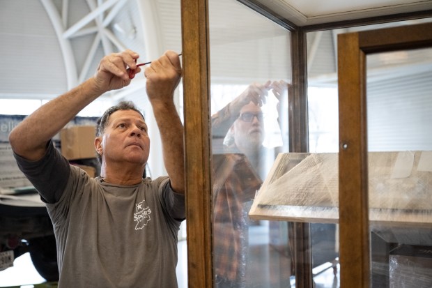 Indiana Welcome Center maintenance worker Dale Gurgel, on left, assists Mario Longoni, lead environmental social scientist with the Field Museum Keller Science Action Center, with a display cabinet in preparation for the upcoming "Calumet Voices, National Stories from the Field Museum" exhibit at the Indiana Welcome Center on Friday, April 5, 2024. (Kyle Telechan/for the Post-Tribune)