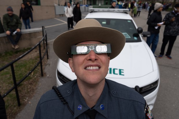 A member of New York State Park Police watches the partial Solar Eclipse on April 8, 2024 in Niagara Falls, New York. Millions of people have flocked to areas across North America that are in the "path of totality" in order to experience a total solar eclipse. During the event, the moon will pass in between the sun and the Earth, appearing to block the sun. (Photo by Adam Gray/Getty Images)