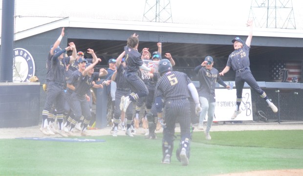 Lemont's Max Michalek (2) jumps as he gets greeted by teammates after scoring a run against Mount Carmel during a Do It Stevie's Way Tournament game in Lemont on Wednesday, April 10, 2024. (Jeff Vorva / Daily Southtown)