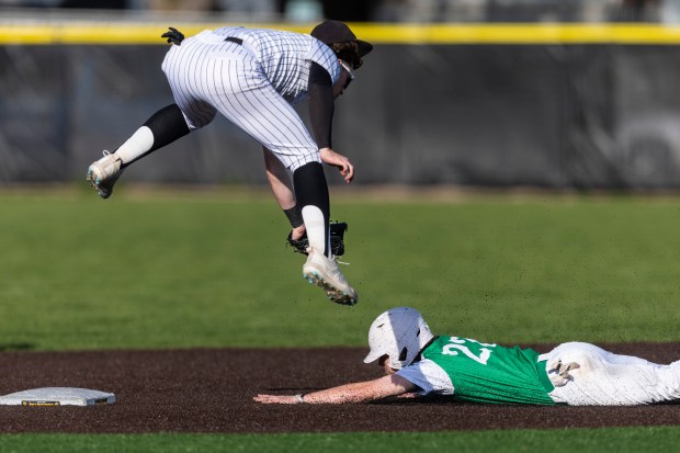 Providence's Mitch Voltz slides under an air-borne Jameson Martin of St. Laurence avoiding a tag during a Chicago Catholic League Blue game in Burbank on Tuesday, April 23, 2024. (Vincent D. Johnson/for the Daily Southtown)