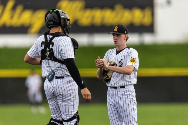 St. Laurence's Declan Musil, right, talks with his catcher Matthew Carrano while St. Rita was at bat with a runner on first during a Chicago Catholic League Blue game in Burbank on Tuesday, April 16, 2024. (Vincent D. Johnson/for the Daily Southtown)