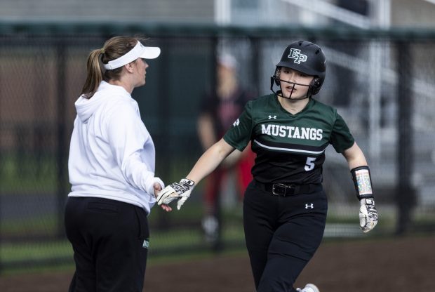 Evergreen Park's Sofia Panatera (5) gets five from her third-base coach after sending a ball over the fence against Mother McAuley during the Southside Showcase in Evergreen Park on Friday, April 12, 2024. (Vincent D. Johnson/for the Daily Southtown)