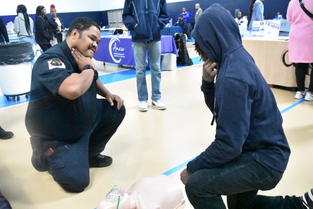 Kameron Younger with the Black Fire Brigade shows a student how to check a person's pulse Saturday. The brigade offers emergency medical services skills training to youth who are interested in a career fighting fires or in the EMS. (Jesse Wright/for Daily Southtown)