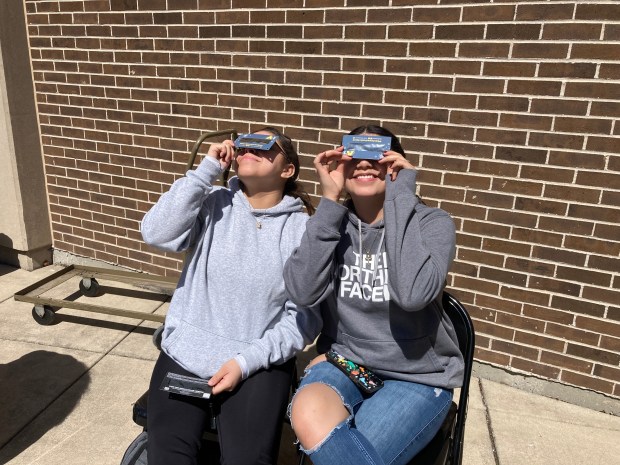 Emily Martinez, left, and Betzaida Ortz watch the solar eclipse April 8, 2024 in the Scholar's Garden at Prarie State College in Chicago Heights. (Alexandra Kukulka/Daily Southtown)