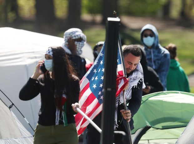 A protester sets down an American flag allegedly belonging to John Brinkmann at the encampment in Deering Meadow at Northwestern University on April 25, 2024, in Evanston. Brinkmann, who was protesting in support of Israel outside of the encampment, said he had an American and an Israeli flag stolen from him. (Stacey Wescott/Chicago Tribune)