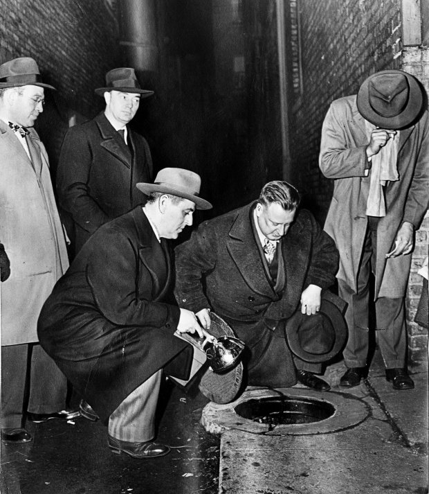 Chief of Detectives Storms, no hat, peers into a catch basin at 5900 Kenmore Ave where Suzanne Degnan's head was found on Jan. 7, 1946. Chicago police officer Lee O'Rourke, who noticed that the soil around the circular edge of the cover was loose, holds the flashlight. William Heirens was convicted of killing Degnan and two other women. (Chicago Tribune archive) 