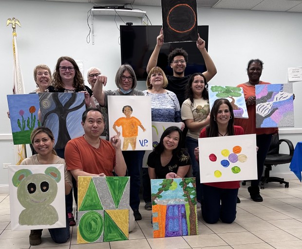 Wearing a red blouse, Avon Township Supervisor Michele Bauman poses with some of the people who attended an art event that aimed to connect and inform on April 8. (Yadira Sanchez Olson/Lake County News-Sun)