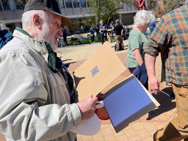 Skokie Resident Norbert Kowalski uses a homemade pinhole viewer to safely view the eclipse at the Skokie Public Library on April 8, 2024. Credit: Richard Requena