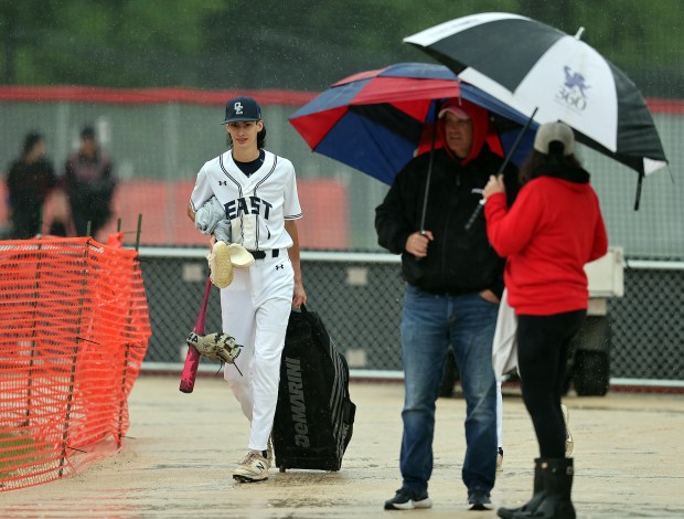 Oswego East's Logan South (1) walks past baseball fans after the Southwest Prairie Conference game against Yorkville was postponed by a steady rain on Thursday, May 9, 2024 in Yorkville.H. Rick Bamman / For the Beacon-News