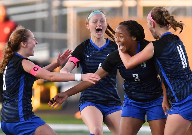 Burlington Central's Mekenzie Rogers (3) is swarmed by teammates Eva Samuelian (left), Rylee Butler, and Kendall Grigg (right) after scoring the first goal against Wheaton Academy during the Class 2A Hinsdale South Supersectional game on Tuesday, May 28, 2024, in Darien.(Jon Cunningham/for The Beacon-News)