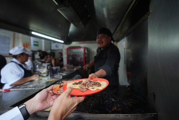 Newly minted Michelin-starred chef Arturo Rivera Martínez hands a customer his order of tacos at the Tacos El Califa de León taco stand, in Mexico City, Wednesday, May 15, 2024. Tacos El Califa de León is the first ever taco stand to receive a Michelin star from the French dining guide. (AP Photo/Fernando Llano)