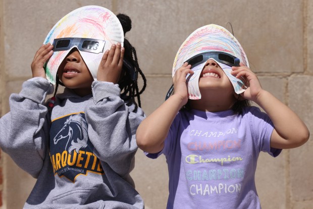 Chole Bernard, 4, and Amor Diaz, 3, preschool students from Marquette Elementary School in Chicago, watch the partial solar eclipse, April 8, 2024. (Antonio Perez/Chicago Tribune)