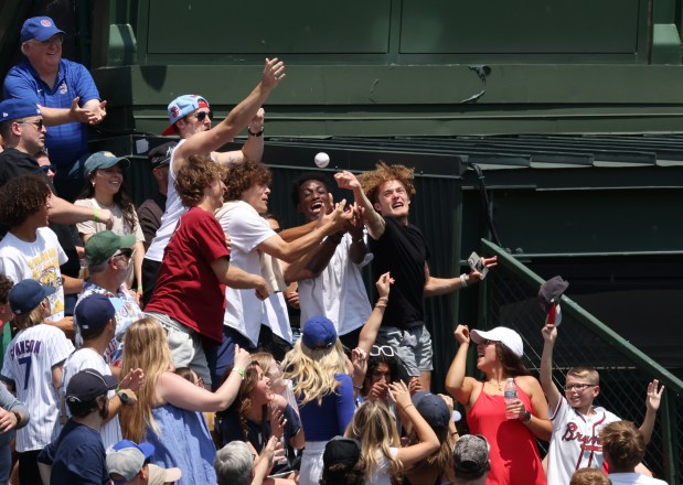 Fans reach for a ball thrown into the bleachers before a game between the Cubs and Braves on May 23, 2024, at Wrigley Field. (John J. Kim/Chicago Tribune)
