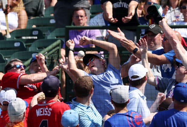 Fans reach for a foul ball hit by Cubs second baseman Nico Hoerner in the sixth inning against the Braves on May 23, 2024, at Wrigley Field. (John J. Kim/Chicago Tribune)