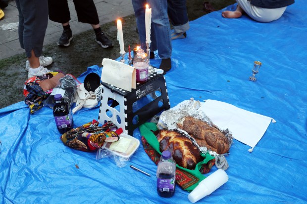 People share challah bread after a shabbat service at the pro-Palestinian encampment on the Main Quad of the University of Chicago on on May 3, 2024. (Terrence Antonio James/Chicago Tribune)