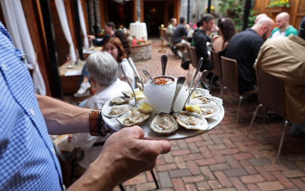 Jon Young, managing partner at Volo Restaurant Wine Bar, 2008 W. Roscoe St., delivers a plate of oysters to a table in the back patio, May 16, 2024, in Chicago. (John J. Kim/Chicago Tribune)